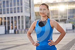 Portrait of attractive sportive middle aged woman in sportswear looking away, standing outdoors ready for running in the