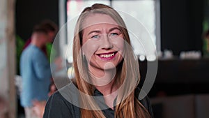 Portrait of attractive successful young blonde entrepreneur business woman cheerfully smiling at camera at trendy office