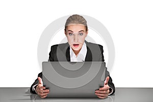 Portrait of attractive surprised young business woman in formal clothes sitting at the desk and looking on laptop display. Concept