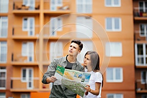 Portrait of an attractive tourist young couple relaxing sightseeing and visiting a destination city on holiday, pointing up and en