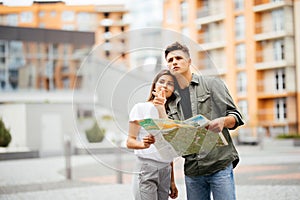 Portrait of an attractive tourist young couple relaxing sightseeing and visiting a destination city on holiday, pointing up and en