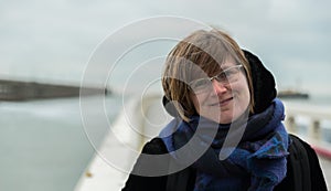 Portrait of an attractive white woman , 30 years old with winter clothes on a windy day at the seaside, Blankenberge