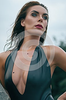 Portrait of an attractive woman in a black leather swimsuit. Fashion photo