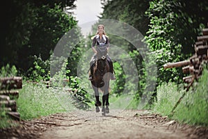 Portrait of attractive woman galloping on black hanoverian stallion horse