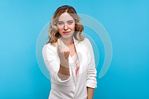 Portrait of attractive woman inviting to come and smiling with seductive look, making beckoning gesture. blue background