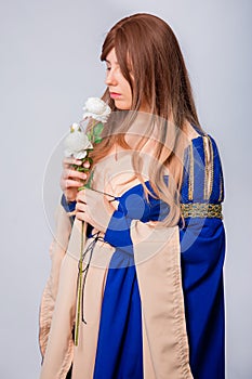 Portrait of an attractive woman with long hair in a medieval, fantasy, blue and beige dress with long, large sleeves,