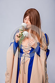 Portrait of an attractive woman with long hair in a medieval, fantasy, blue and beige dress with long, large sleeves,