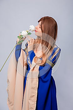 Portrait of an attractive woman with long hair in a medieval, fantasy, blue and beige dress with long, large sleeves,