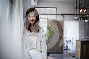 Portrait of an attractive woman looking at camera and cheerful smiling at the window