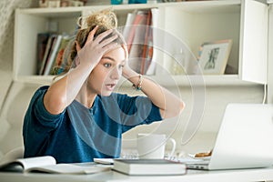 Portrait of an attractive woman at table grabbing her head