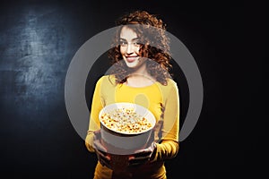 Portrait of attractive woman treating to popcorn with cheerful smile
