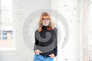 Portrait of attractive woman wearing roll neck sweater and jeans while looking at camera and smiling photo