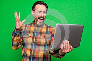 Portrait of attractive worried man using laptop reading finance report fail isolated over bright green color background