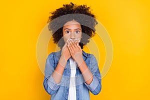 Portrait of attractive worried teen age small little girl closing mouth oops isolated over vibrant yellow color