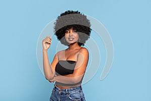 Portrait of attractive young African American female model in black top and jeans, with afro hairstyle, looking to the camera. A
