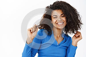 Portrait of attractive young african american woman with curly hair, posing with happy beautiful smile, looking at
