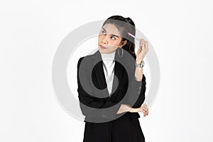 Portrait of attractive young Asian business woman holding pen and having idea posing over white isolated background