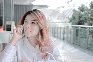 Portrait of attractive young Asian business woman talking on phone for her job in office with copy space background.