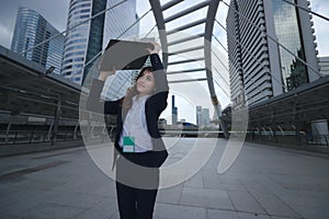 Portrait of attractive young Asian business woman walking and raising document folder at sidewalk of urban city background