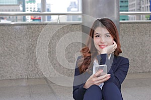 Portrait of attractive young Asian leaning a pole and looking to camera at urban building against copy space background