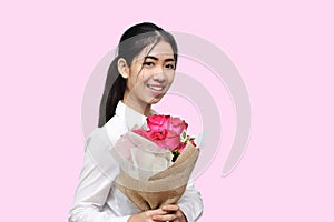Portrait of attractive young Asian woman holding a bouquet of red roses on pink isolated background. Valentine`s day concept.