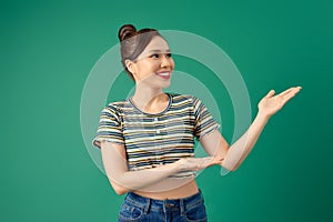 Portrait attractive young Asian woman holding copyspace on the palm isolated on green background