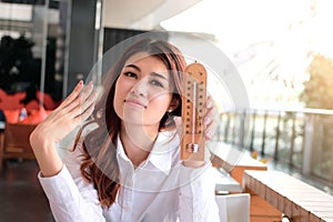 Portrait of attractive young Asian woman holding thermometer and feeling so hot. Summer time