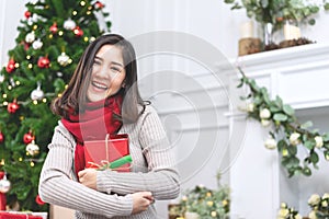 Portrait of attractive young asian woman or teenage girl smiling and looking at camera holding red gift or christmas present