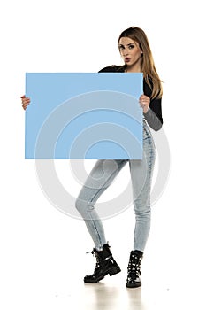 Portrait of attractive young beautiful woman holding blank blue billboard