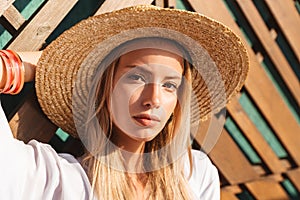 Portrait of attractive young blond woman 20s in straw hat and sw