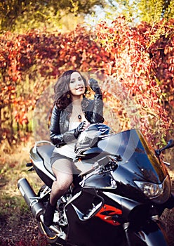 Portrait of an attractive young brunette woman biker posing on h