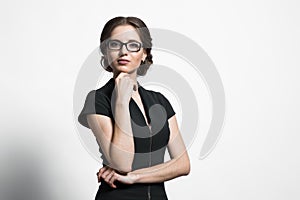 Portrait of attractive young caucasian business woman holding hand near her chin on grey background