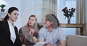 Portrait of attractive young couple chatting with their real estate agent on the sofa they have a discussing about house