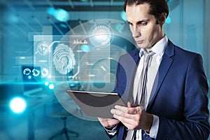 Portrait of attractive young european businessman using tablet with abstract glowing fingerprint interface on blurry office
