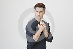 Portrait of attractive young european student, standing in profile while showing gun gesture, acting like spy or soldier