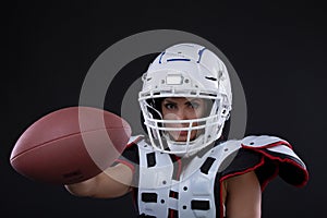Portrait of attractive young girl in a sports outfit for rugby with the helmet strongly looking forward standing on black bac