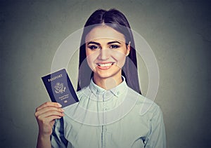 Portrait attractive young happy woman with USA passport on gray wall background. Positive human emotions face expression.