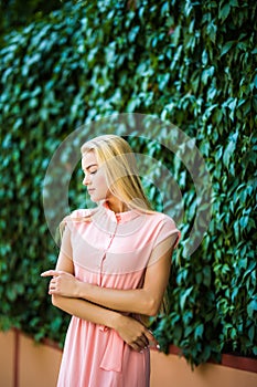 Portrait of attractive young sensual woman on a background of ivy wall with green leaves