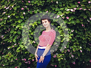 Portrait of an attractive young sensual woman on a background of ivy wall with green leaves.