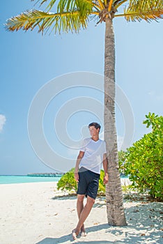 Portrait of attractive young sexy man wearing t-shirt and shorts at tropical beach at island luxury resort