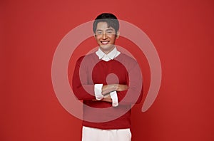 Portrait of attractive young southeast Asian man standing with crossed arms isolated on red background