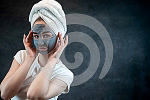 Portrait of attractive young woman apply clay mud mask on her face isolated on black