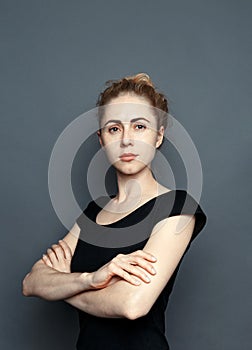 Portrait Of Attractive Young Woman With Arms Crossed On Gray Background