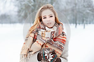 Portrait of an attractive young woman with brown eyes with a stylish woolen vintage beautiful scarf in mittens