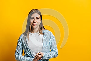 Portrait of attractive young woman with brunette hair and crossed arms looking on camera. isolated on yellow background, studio