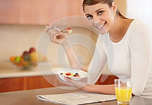 Enjoying a healthy breakfast. Portrait of an attractive young woman eating her breakfast in the kitchen.