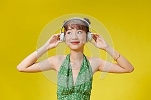 Portrait of an attractive young woman isolated over pink, listening to music with headphones