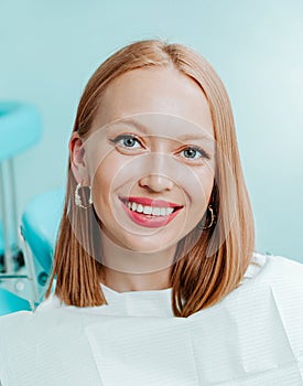 Portrait of attractive young woman with natural white teeth in light blue background in dental clinic. Smile healthy teeth concept