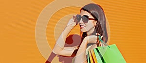 Portrait of attractive young woman with shopping bags over orange background
