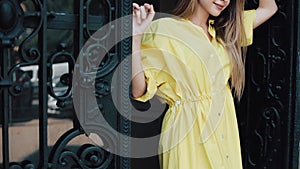 Portrait of an attractive young woman standing on the street of a European city in a yellow dress and looking into